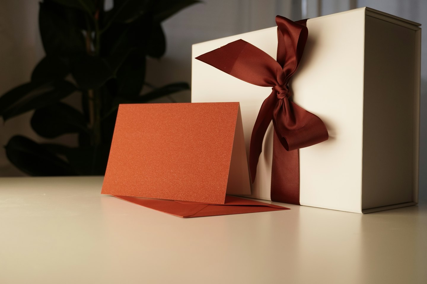 A white gift box with a red ribbon beside stationery.